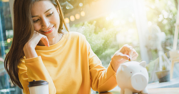 4 Millennial-Friendly Ways to Invest from Your Smartphone (for $100 or Less) Asian woman saving money and dropping coin to piggy