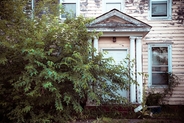 Should You Buy Properties With Back Taxes or Liens? Exterior facade on abandoned foreclosed home
