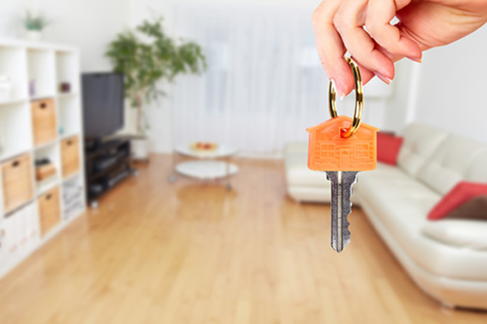 3 Levels of House Hacking: How to Reduce—or Eliminate—Your Housing Expense person holding house key with living room in background