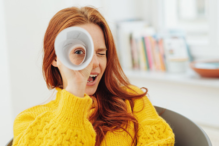 Why You Need to Stop Caring About Most Things woman looking through rolled up paper suggesting focusing on one thing