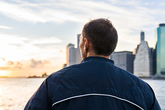 What Are Opportunity Zones—and Why Should Real Estate Investors Care? man looking out over river at cityscape and sunset
