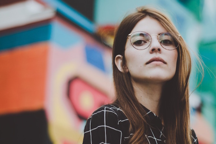 Why You Should Stop Walking Away from Imperfect Deals woman in plaid shirt with glasses standing in front of colorfully painted building