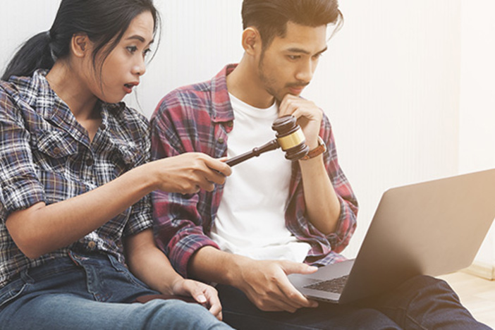 3 Hidden Pitfalls of Online Auctions (& How to Avoid Them) couple on laptop, on holding gavel, online auction concept