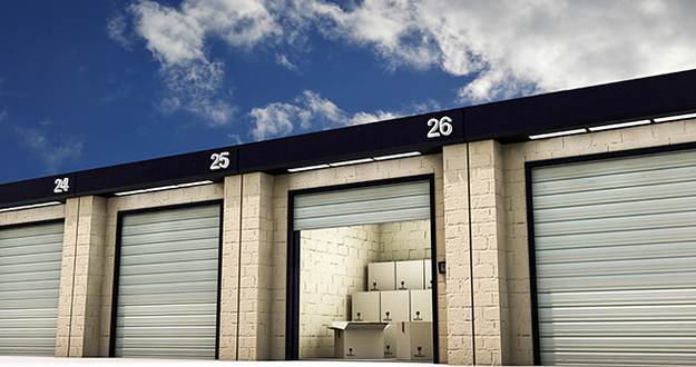 Why Self-Storage Investing Is Red Hot self-storage facility with garage door open and packed boxes stacked inside