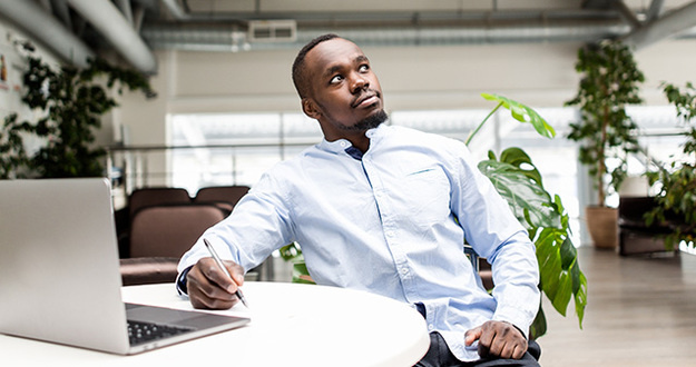 3 Tax Tips for Vacation Rental Owners Pensive African man sitting in the office at the table making notes in a notebook