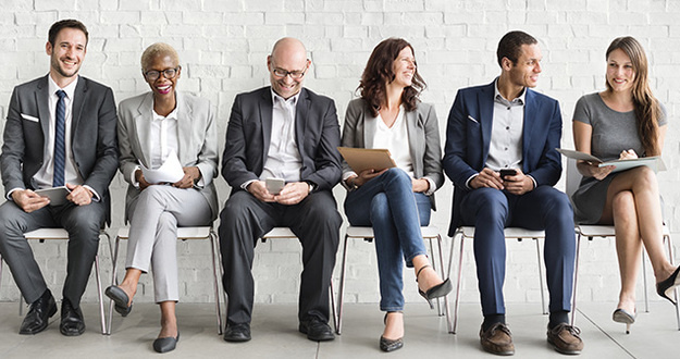 The Ultimate Guide to Interviewing Property Managers Group of diverse people are seated and waiting for a job interview in a waiting room with white walls and light colored floor