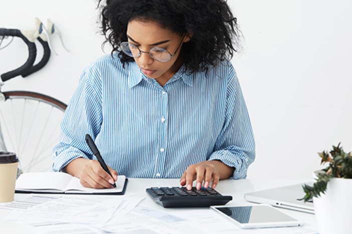 No Credit? Bad Credit? 6 Steps to Fix Your Finances businesswoman doing paperwork at office desk, working through finances, using calculator and making notes in her notebook with pen