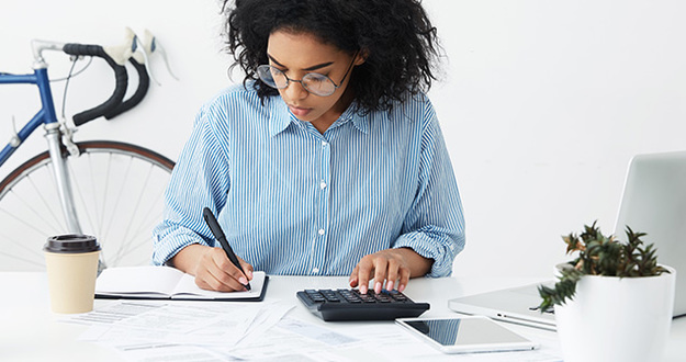 No Credit? Bad Credit? 6 Steps to Fix Your Finances businesswoman doing paperwork at office desk, working through finances, using calculator and making notes in her notebook with pen