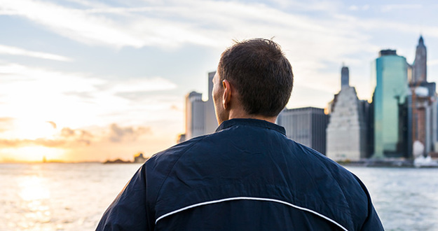 Renting a Home Is Financially Better Than Buying—Wait, What?! man looking out over river at cityscape and sunset