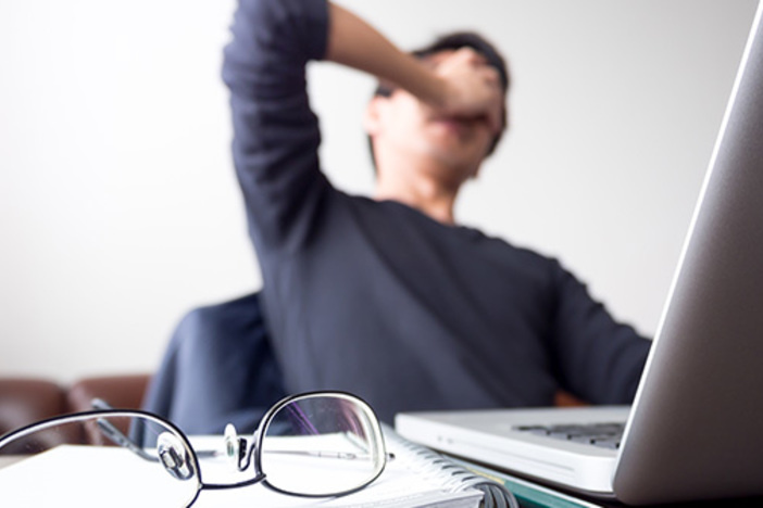 Don’t Panic If Your Buyer Defaults! How to Save a Deal Gone Sour man at desk with hand covering face taking a break from work with glasses and open laptop on desk symbolizing stress, frustration