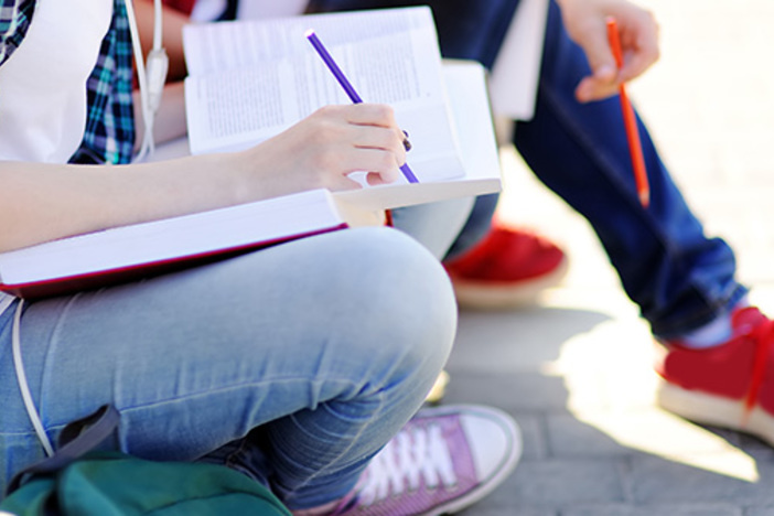 Personal Finance Classes Should Absolutely Be Required for Students Close up photo of young happy students with books and notes outdoors. Smart young guy and girl in University campus. Learning and education for young people.