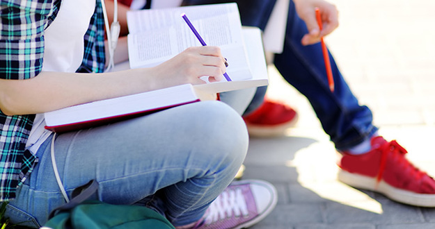 Personal Finance Classes Should Absolutely Be Required for Students Close up photo of young happy students with books and notes outdoors. Smart young guy and girl in University campus. Learning and education for young people.