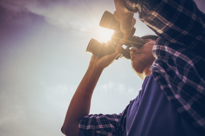 27 Ways to Find Real Estate Deals Close-up Of Asian man Hand Holding / looking / watching using Binoculars with copyspace, Technology Binoculars background concept