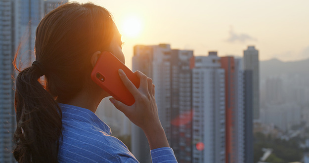 The 20 Best Performing Opportunity Zones for Real Estate Investors Woman talking on cellphone with the city background under sunlight