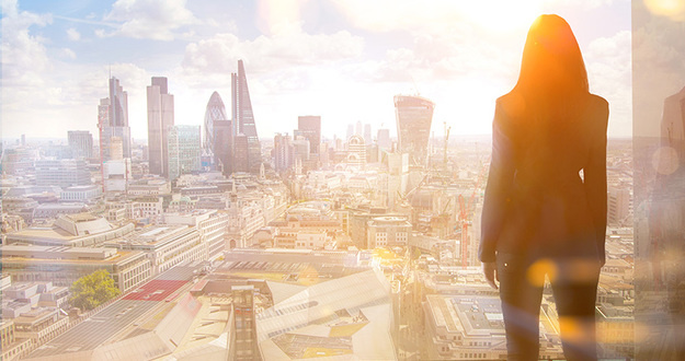 3 Tips for Getting Approved for a Commercial Loan (& 3 Types of Commercial Lenders—Explained) Young woman looking over the City of London at sun set.