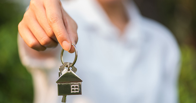 Opinion: THIS Is Hands Down the Best Way to Buy Property house key in woman hand and green leaves background