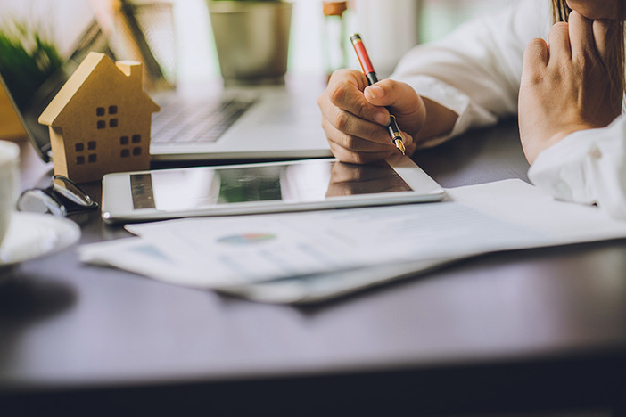 Private Real Estate Investing: When Does It Make Sense? Hand of Business people calculating interest, taxes and profits to invest in real estate and home buying