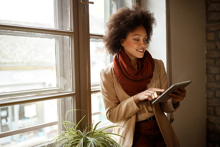 No Money Down Loans: How Do They REALLY Work? Young Afro-American woman near window on workplace taking information from ipad