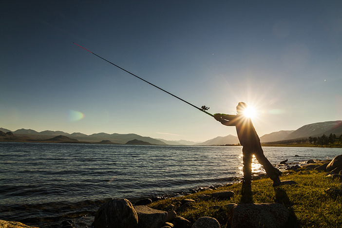 How to Retire Early (From Someone Who Did at Age 27) Silhouette of a fisherman at sunset. Fishing on mountain lake