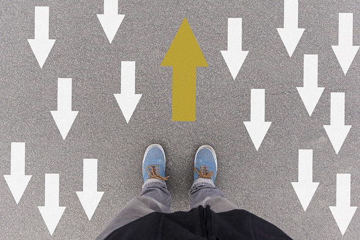3 Reasons Newbie Investors Should Hire a Coach Opposing direction arrows on asphalt ground, feet and shoes on floor, personal perspective footsie concept for finding your own way