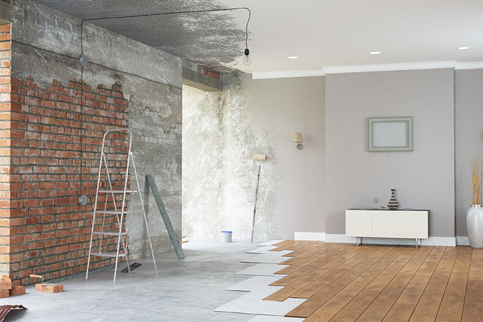 Flipping Houses: The 6 Most Important Calculations When Assessing a Fix & Flip renovation interior with vinyl plank flooring and faux brick wall and gray paint