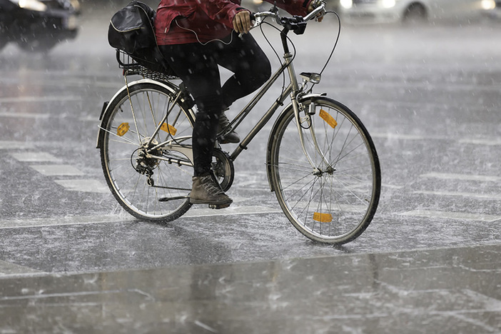 7 Steps to Managing Your Money in a Volatile Economy closeup of lower half of a person riding a bicycle in heavy rain on city street