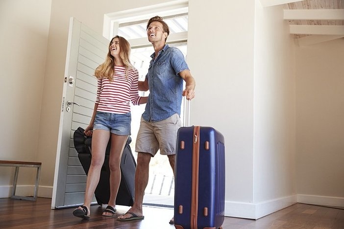 10 Things You Didn’t Know About Airbnb Couple walking in front door of vacation rental with suitcases