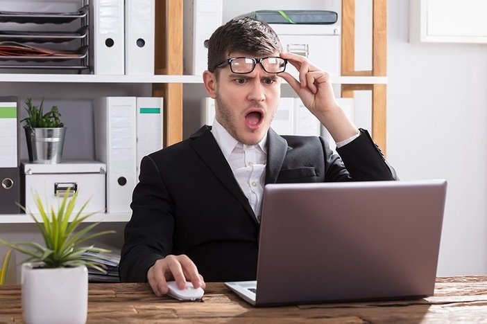 How Much Debt Is Too Much When It Comes To Real Estate? Shocked Young Businessman Looking At Laptop In Office