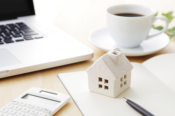 Rent to Own Homes: How to Profit from a Lease Purchase wooden model of house on desk with coffee cup, calculator, laptop