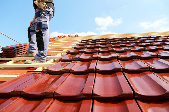 4 Home Improvement Jobs You Should ALWAYS Hire Out worker standing on roof installing new tiles