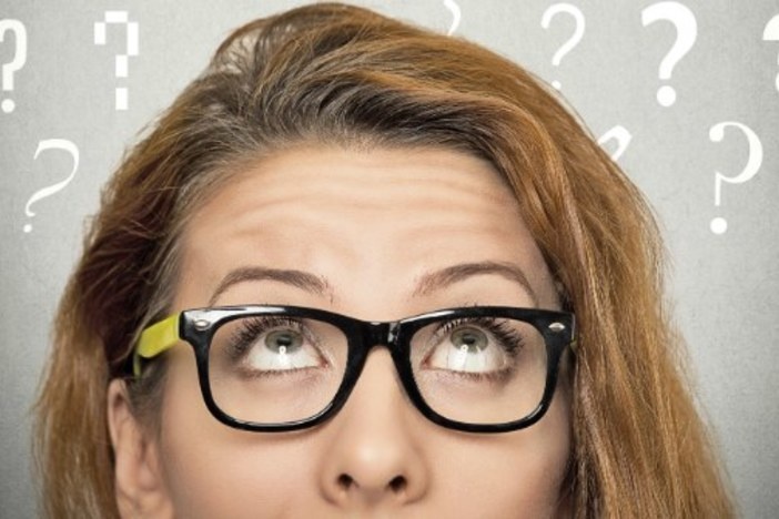 6 Questions to Ask Yourself at the Year’s End for a Better Business in 2015 top half of red haired woman's head with blackboard in background question marks written in chalk
