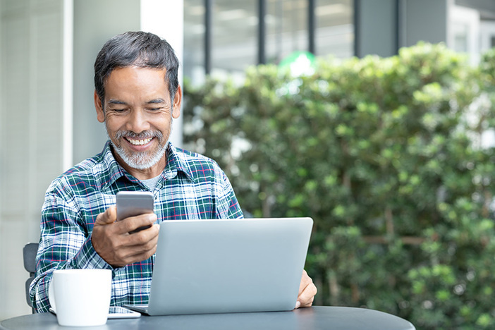 5 Things You Probably Didn’t Know Your Title Company Could Do for You Smiling happy mature man with white stylish short beard using smartphone gadget serving internet at coffee shop cafe outdoor. Laughing old man using social media network technology feeling excited.