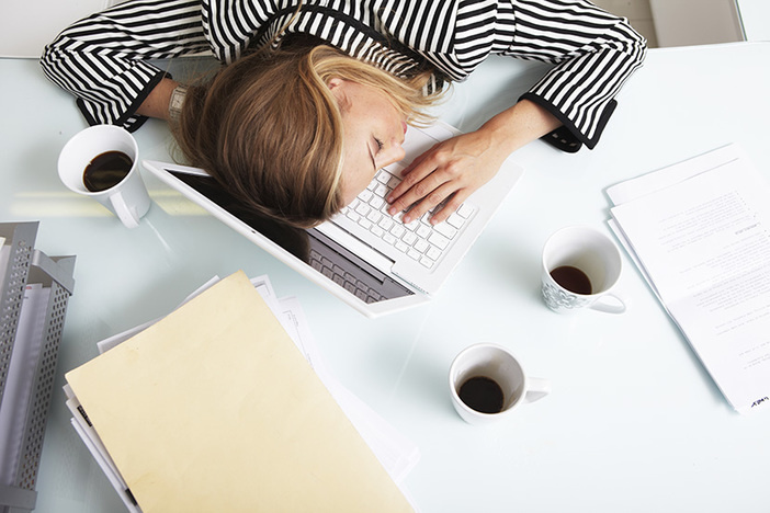 How to Save Your Willpower by Avoiding Decision Fatigue female in black striped shirt laying head on laptop three coffees, file folders, paperwork on desktop